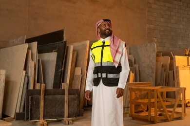 Quality of local production, home and office furniture industry, a Saudi Arabian Gulf engineer man wearing traditional thobe and work clothes looking at something with happy gestures, standing straight with expressions of pleasure, workshops in Saudi Arabia, tools and equipment made of marble
