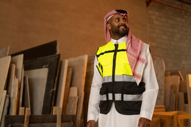 Quality of local production, home and office furniture industry, a Saudi Arabian Gulf engineer man wearing traditional thobe and work clothes looking at something with happy gestures, standing straight with expressions of pleasure, workshops in Saudi Arabia, tools and equipment made of marble