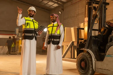 Pointing to something, workshops in Saudi Arabia, tools and equipment made of marble, quality of local national production, home and office furniture manufacturing, two Saudi Arabian Gulf Arab engineers wearing traditional thobes and work clothes working on a tablet, integrating technology and technology in laboratories