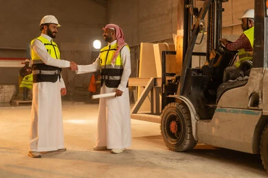 السلام والترحيب والمصافحة، ورشات عمل في السعودية, أدوات ومعدات مصنوعة من الرخام, جودة الانتاج المحلي الوطني, مهن وحرف شعبية تقليدية قديمة في المملكة, صناعة الأثاث المنزلي والمكتبي، رجل مهندس عربي خليجي سعودي يرتدي الثوب التقليدي وزي العمل يصافح زميله