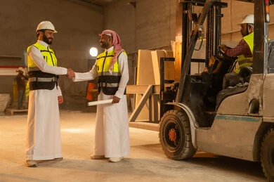 الترحيب والسلام والمصافحة، ورشات عمل في السعودية, أدوات ومعدات مصنوعة من الرخام, جودة الانتاج المحلي الوطني, مهن وحرف شعبية تقليدية قديمة في المملكة, صناعة الأثاث المنزلي والمكتبي، رجل مهندس عربي خليجي سعودي يرتدي الثوب التقليدي وزي العمل يصافح زميله