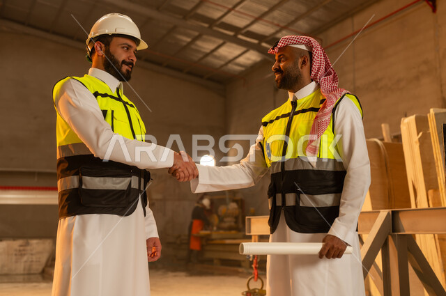 السلام والترحيب والمصافحة، ورشات عمل في السعودية, أدوات ومعدات مصنوعة من الرخام, جودة الانتاج المحلي الوطني, مهن وحرف شعبية تقليدية قديمة في المملكة, صناعة الأثاث المنزلي والمكتبي، رجل مهندس عربي خليجي سعودي يرتدي الثوب التقليدي وزي العمل يصافح زميله