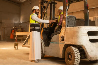 Peace, welcome and handshake, workshops in Saudi Arabia, tools and equipment made of marble, quality of local national production, old traditional professions and crafts in the Kingdom, home and office furniture manufacturing, a Saudi Arabian Gulf Arab engineer wearing traditional thobe and work clothes shaking hands with his colleague