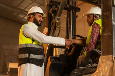 Greetings, greetings, and handshakes. Workshops in Saudi Arabia. Marble tools and equipment. Quality local national production. Traditional folk professions and crafts in the Kingdom. Home and office furniture manufacturing. A Saudi Arabian Gulf engineer wearing traditional clothing and work clothes shakes hands with his colleague.