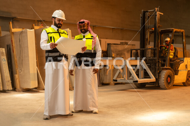 تبادل الآراء والخبرات، ورشات عمل في المملكة العربية السعودية, أدوات ومعدات مصنوعة من الرخام, جودة الانتاج المحلي الوطني, صناعة الأثاث المنزلي والمكتبي، رجل مهندس عربي خليجي سعودي يرتدي الثوب التقليدي وزي العمل يتناقش مع زميله