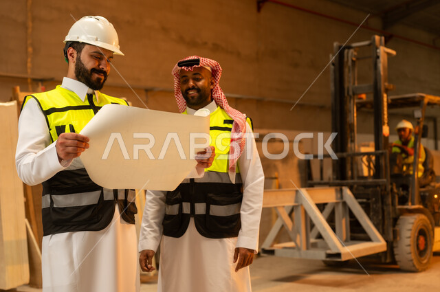 تبادل الآراء والخبرات، ورشات عمل في المملكة العربية السعودية, أدوات ومعدات مصنوعة من الرخام, جودة الانتاج المحلي الوطني, صناعة الأثاث المنزلي والمكتبي، رجل مهندس عربي خليجي سعودي يرتدي الثوب التقليدي وزي العمل يتناقش مع زميله