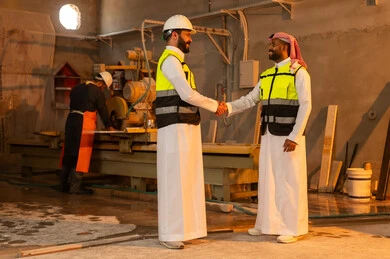 المصافحة والسلام والترحيب، ورشات عمل في السعودية, أدوات ومعدات مصنوعة من الرخام, جودة الانتاج المحلي الوطني, مهن وحرف شعبية تقليدية قديمة في المملكة, صناعة الأثاث المنزلي والمكتبي، رجل مهندس عربي خليجي سعودي يرتدي الثوب التقليدي وزي العمل يصافح زميله