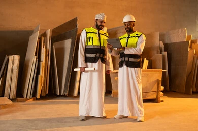 Quality of local national production, home and office furniture industry, two Omani Gulf Arab engineers wearing dishdashas and work clothes working on a tablet, integrating technology and technology in laboratories, factories and workshops of the Sultanate of Oman, tools and equipment made of marble