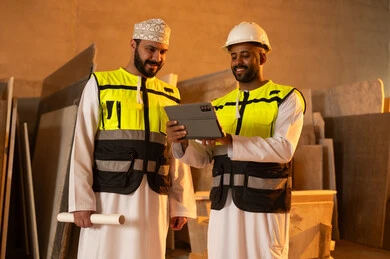 مصانع ومعامل سلطنة عمان, أدوات ومعدات مصنوعة من الرخام، جودة الانتاج المحلي الوطني, صناعة الأثاث المنزلي والمكتبي، رجلان مهندسان عربيان خليجيان عمانيان يرتديان الدشداشة وزي العمل يعملان على جهاز التابلت، دمج التقنية والتكنولوجيا في المعامل