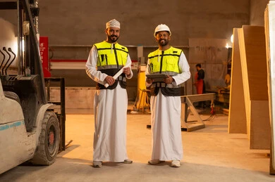 Factories and plants of the Sultanate of Oman, tools and equipment made of marble, quality of local national production, home and office furniture industry, two Omani Gulf Arab engineers wearing dishdashas and work clothes working on a tablet, integrating technology and technology in laboratories