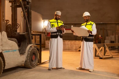 Factories and plants of the Sultanate of Oman, tools and equipment made of marble, quality of local national production, home and office furniture industry, two Omani Gulf Arab engineers wearing dishdashas and work clothes working on a tablet, integrating technology and technology in laboratories