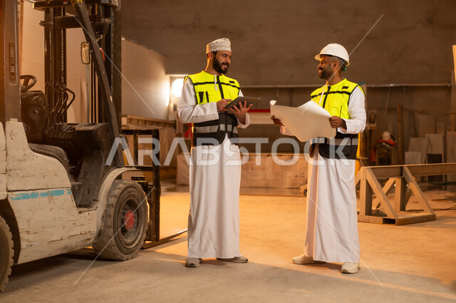 جودة الانتاج المحلي الوطني, صناعة الأثاث المنزلي والمكتبي، رجلان مهندسان عربيان خليجيان عمانيان يرتديان الدشداشة وزي العمل يعملان على جهاز التابلت، دمج التقنية والتكنولوجيا في المعامل، مصانع ومعامل سلطنة عمان, أدوات ومعدات مصنوعة من الرخام