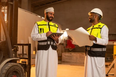 Quality of local national production, home and office furniture industry, two Omani Gulf Arab engineers wearing dishdashas and work clothes working on a tablet, integrating technology and technology in laboratories, factories and workshops of the Sultanate of Oman, tools and equipment made of marble