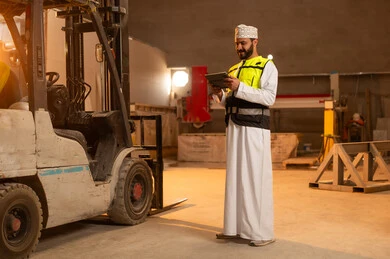 دمج التقنية والتكنولوجيا في المعامل، ورشات عمل في سلطنة عمان, أدوات ومعدات مصنوعة من الرخام، جودة الانتاج المحلي الوطني, صناعة الأثاث المنزلي والمكتبي، رجل مهندس عربي خليجي عمانب يرتدي الدشداشة وزي العمل يمسك بيده جهاز التابلت