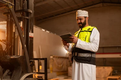 Integrating technology and technology in laboratories, workshops in the Sultanate of Oman, tools and equipment made of marble, quality of local national production, home and office furniture manufacturing, an Arab Gulf Omani engineer man wearing a dishdasha and work clothes holding a tablet in his hand