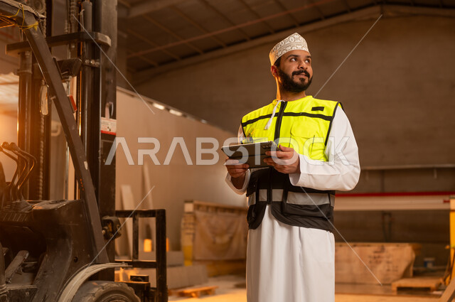 Integrating technology and technology in laboratories, workshops in the Sultanate of Oman, tools and equipment made of marble, quality of local national production, home and office furniture manufacturing, an Arab Gulf Omani engineer man wearing a dishdasha and work clothes holding a tablet in his hand