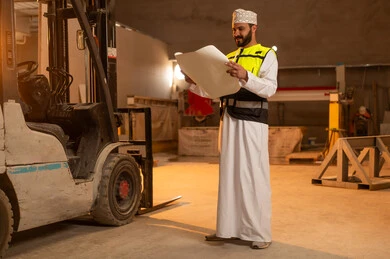 صنع منتج وطني محلي, صناعة الأثاث المنزلي والمكتبي، العمل على المخططات والاوراق الهندسية، رجل مهندس عربي خليجي عماني يرتدي الدشداشة وزي العمل يمسك بيده الورقة، ورشات عمل في سلطنة عمان، أدوات ومعدات مصنوعة من الرخام