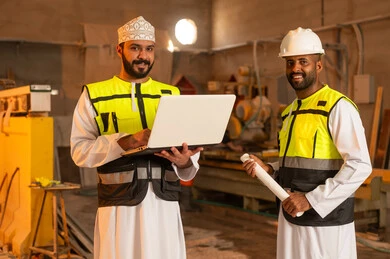 صناعة الأثاث المنزلي والمكتبي، رجلان مهندسان عربيان خليجيان عمانيان يرتديان الدشداشة وزي العمل يعملان على الحاسب المحمول، دمج التقنية والتكنولوجيا في المعامل، ورشات عمل في سلطنة عمان، أدوات ومعدات مصنوعة من الرخام، جودة الانتاج المحلي الوطني