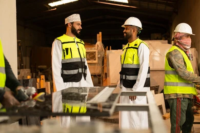 تبادل الآراء والخبرات، ورشات عمل في سلطنة عمان, أدوات ومعدات مصنوعة من الرخام, جودة الانتاج المحلي الوطني, صناعة الأثاث المنزلي والمكتبي، رجل مهندس عربي خليجي عماني يرتدي الدشداشة وزي العمل يتناقش مع زميله