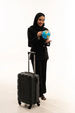 تحديد مسار سير الرحلة، البحث والاستكشاف حول العالم، مفهوم السياحة والسفر، القيام بجولات سياحية ترفيهية،  بورتريه لامرأة عربية سعودية خليجية محجبة ترتدي البدلة الرسمية السوداء تقف باستقامة و تقوم بجر حقيبة الامتعة و تحمل بيدها  مجسم الكرة الارضية, خلفية بيضاء