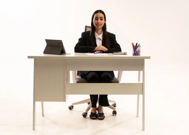 مهن ووظائف مكتبية إدارية نسائية في السعودية، إنجاز المهام المطلوبة أونلاين، دمج العمل مع التكنولوجيا الحديثة، بورتريه لامرأة عربية سعودية خليجية تجلس خلف المكتب ترتدي البدلة الرسمية السوداء و تستخدم التابلت و تنظر للكاميرا بالسعادة, خلفية بيضاء