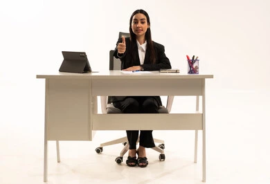 الإمتياز والتميز والنجاح، دمج العمل مع التكنولوجيا الحديثة، بورتريه لامرأة عربية سعودية خليجية تجلس خلف المكتب ترتدي البدلة الرسمية السوداء و تستخدم التابلت و ترفع أصابع الإبهام لأعلى بعلامة اللايك, خلفية بيضاء