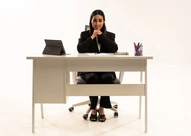 الجلوس في المكتب والنظر إلى الكاميرا, انجاز مهام العمل عبر الانترنت,  بورتريه لامرأة عربية سعودية خليجية تعمل في الشركة ترتدي البدلة الرسمية السوداء و تستخدم التابلت, استخدام التقنيات الحديثة المتطورة، خلفية بيضاء