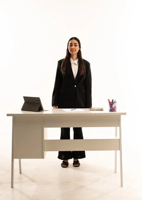 التميز في العمل, التعليم المتطور في مدارس المملكة العربية السعودية, بورتريه لمعلمه عربيه سعوديه خليجيه ترتدي البدله الرسميه السوداء تقف امام مكتب ابيض و تستخدم جهاز التابلت, ايماءات الثقة و السعادة, خلفية بيضاء