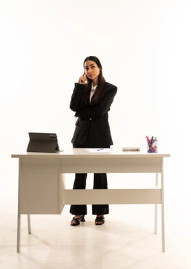 تعزيز العلوم والإبتكارات, التعليم المتطور في مدارس المملكة العربية السعودية, بورتريه لمعلمه عربيه سعوديه خليجيه ترتدي البدله الرسميه السوداء تقف امام مكتب ابيض و تستخدم جهاز التابلت, ايماءات التفكير و الانشغال, خلفية بيضاء