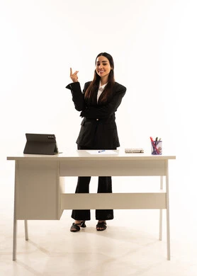 Advanced education in Saudi Arabian schools: Portrait of a Saudi Arabian teacher wearing a black formal suit, standing in front of a white desk and pointing at something. Explanation using a tablet. Full-length portrait. White background.