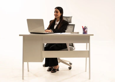 إنجاز المهام المطلوبة أونلاين، دمج العمل مع التكنولوجيا الحديثة، إجراء الاعمال المكتبيه داخل مقر الشركه عبر اللابتوب، بورتريه لامرأة عربية سعودية خليجية ترتدي البدلة الرسمية السوداء و تستخدم الحاسب المحمول, خلفية بيضاء