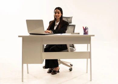 Office-based job, completing tasks online, integrating work with modern technology. Portrait of a Saudi Arabian woman wearing a black formal suit, using a laptop, and looking at the camera with happy and joyful expressions, white background