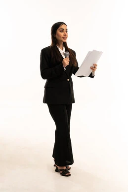 فن التحدث والخطابة، القيام بالحوارات والنقاشات، القاء الخطابات والكلمات باستخدام مكبر الصوت, بدء التدريب الصوتي، بورتريه لامرأة عربية سعودية خليجية مبتسمة ترتدي البدلة الرسمية السوداء تقف باستقامة و تمسك بيدها المايكروفون و الأوراق, خلفية بيضاء
