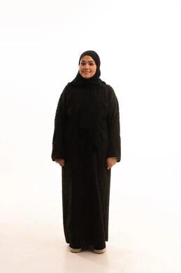 الوقوف باستقامة والنظر إلى الكاميرا، بورتريه لامرأة عربية خليجية سعودية محجبة ترتدي عباءة سوداء تقف  بإيماءات الثقة بالنفس، مفهوم الأناقة والاهتمام بالمظهر الخارجي، صورة الجسم بالطول الكامل، خلفية بيضاء