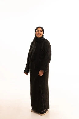 The concept of elegance and concern for one's outward appearance, standing straight and looking at something, portrait of a veiled Saudi Arabian Gulf woman wearing a black abaya standing with gestures of self-confidence, full-length body image, white background