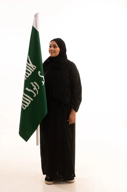 Commemorating the founding of the first Saudi state in 1727 AD, pride in the achievements of the Kingdom, the day we began, February 22, showing loyalty and love for the homeland, portrait of a Saudi Arabian Gulf woman wearing a hijab and abaya holding the founding flag with gestures of pride and loftiness, full-length body, white background