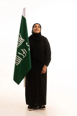 Anniversary of the founding of the first Saudi state 1727 AD, pride in the achievements of the Kingdom, the day we began, February 22, showing loyalty and love for the homeland, portrait of a Saudi Arabian Gulf woman wearing a hijab and abaya holding the founding flag with gestures of pride and loftiness, full-length body, white background
