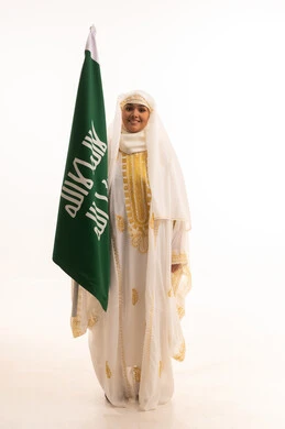 الاحتفال بالأعياد الوطنية الشعبية، ارتداء أزياء المنطقة الشرقية، يوم العلم السعودي11 مارس، يوم بدينا 1727 م، بورتريه لإمرأة عربية خليجية سعودية مبتسمة ترتدي الشيلة والنشل تحمل بيدها علم يوم تأسيس الدولة السعودية الأولى، الجسم بالطول الكامل، خلفية بيضاء