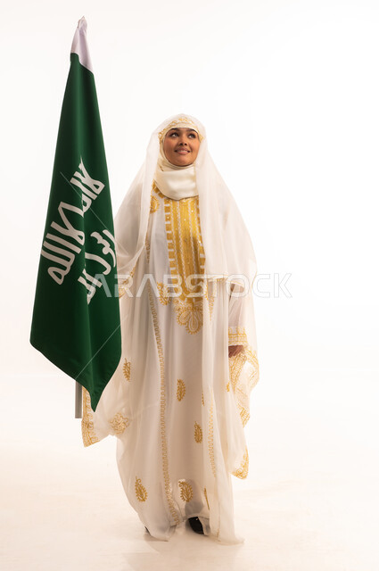 يوم العلم السعودي11 مارس، يوم بدينا 1727 م، ارتداء أزياء المنطقة الشرقية، بورتريه لإمرأة عربية خليجية سعودية مبتسمة ترتدي الشيلة والنشل تحمل بيدها علم يوم تأسيس الدولة السعودية الأولى، الاحتفال بالأعياد الوطنية الشعبية، الجسم بالطول الكامل، خلفية بيضاء