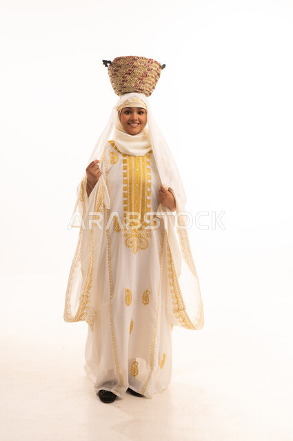 يوم بدينا١٧٢٧م، مهن وحرف يدوية شعبية قديمة، النظر إلى الكاميرا بتعابير الفخر والاعتزاز، بورتريه لامرأة عربية خليجية سعودية مبتسمة ترتدي الشيلة والنشل تمسك تضع على رأسها سلة قش، ارتداء أزياء المنطقة الشرقية، ذكرى تأسيس الدولة السعودية الأولى٢٢فبراير، خلفية بيضاء