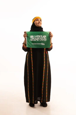 Pride and boasting of the country's achievements, pride in historical heritage, Flag Day March 11, the day we started in 1727 AD, wearing the Central Region costume, Saudi National Day September 23, portrait of a Saudi Arabian Gulf woman wearing a kurta and a head holding the Kingdom's flag, full-length body, white background