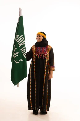 الاحتفال بالمناسبات والأعياد الوطنية الشعبية، ذكرى تأسيس الدولة السعودية الأولى 22 فبراير، يوم بدينا 1727 م، ارتداء أزياء المنطقة الوسطى، بورتريه لإمرأة عربية خليجية سعودية مبتسمة ترتدي الكرتة والهامة تحمل بيدها علم يوم التأسيس، الجسم بالطول الكامل، خلفية بيضاء