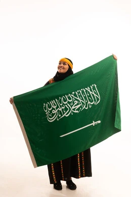 The Day We Began 1727 AD, pride and boasting about the country's achievements, pride in historical heritage, Flag Day March 11, wearing the Central Region costume, Saudi National Day September 23, portrait of a Saudi Arabian Gulf woman wearing a kurta and a head holding the Kingdom's flag, full-length body, white background