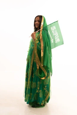 اليوم الوطني السعودي 23 سبتمبر، رفع راية التوحيد والإسلام، يوم العلم 11 مارس، ارتداء الزي الشعبي للمنطقة الوسطى في مناسبة وطنية, يوم بدينا22 فبراير, بورتريه من الجانب لامرأة عربية خليجية سعودية ترتدي الشيلة والبشت تمسك علم المملكة، الطول الكامل للجسم، خلفية بيضاء