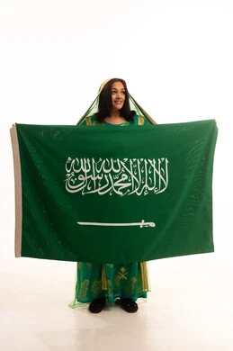 Raising the banner of monotheism and Islam, Flag Day, March 11, wearing the traditional costume of the Central Region on a national occasion, Badina Day, February 22, Saudi National Day, September 23, portrait of a Saudi Arabian Gulf woman wearing a shayla and bisht holding the flag of the Kingdom, full body length, white background
