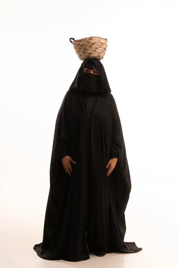 الاحتفال بيوم بدينا ١٧٢٧م، مشغولات يدوية نسائية، حرف وأعمال شعبية تقليدية، ذكرى تأسيس الدولة السعودية الاولى ٢٢ فبراير، بورتريه لسيدة عربية خليجية سعودية ترتدي البرقع والعباءة السوداء تضع على رأسها سلة مصنوعة من القش، صورة لكامل الجسم، خلفية بيضاء