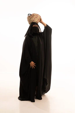 الاحتفال بيوم بدينا ١٧٢٧م، مشغولات يدوية نسائية، حرف وأعمال شعبية تقليدية، ذكرى تأسيس الدولة السعودية الاولى ٢٢ فبراير، بورتريه لسيدة عربية خليجية سعودية ترتدي البرقع والعباءة السوداء تضع على رأسها سلة مصنوعة من القش، صورة لكامل الجسم، خلفية بيضاء