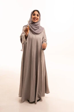The concept of healthy habits, maintaining and continuously cleaning teeth, a bright white smile, daily oral hygiene routine, avoiding cavities and gum diseases, a portrait of a Saudi Gulf Arab woman wearing a hijab and abaya holding a toothbrush in her hands, full body, white background.