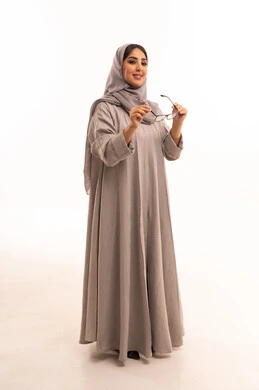 تحسين القدرة البصرية للعين، مفهوم ضعف النظر، اقتناء نظارات طبية جديدة، متعة التسوق في السعودية، بورتريه لامرأة عربية خليجية سعودية ترتدي الحجاب و العباءة تقوم باختيار نظارة ملائمة لملامح الوجه، الجسم بالطول الكامل، خلفية بيضاء