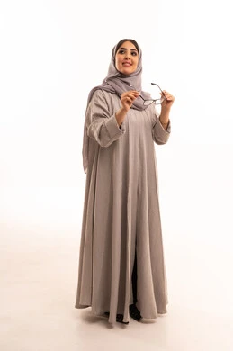 تحسين وضوح الرؤية للعين، مفهوم ضعف النظر، اقتناء نظارات طبية جديدة، متعة التسوق في السعودية، بورتريه لامرأة عربية خليجية سعودية ترتدي الحجاب و العباءة تقوم باختيار نظارة ملائمة لملامح الوجه، الجسم بالطول الكامل، خلفية بيضاء